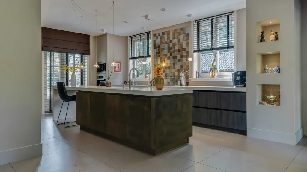Luxe maatwerkkeuken in Oosterbeek met een uniek messing kookeiland, een handgemaakte tegelwand en een sfeervolle inrichting.