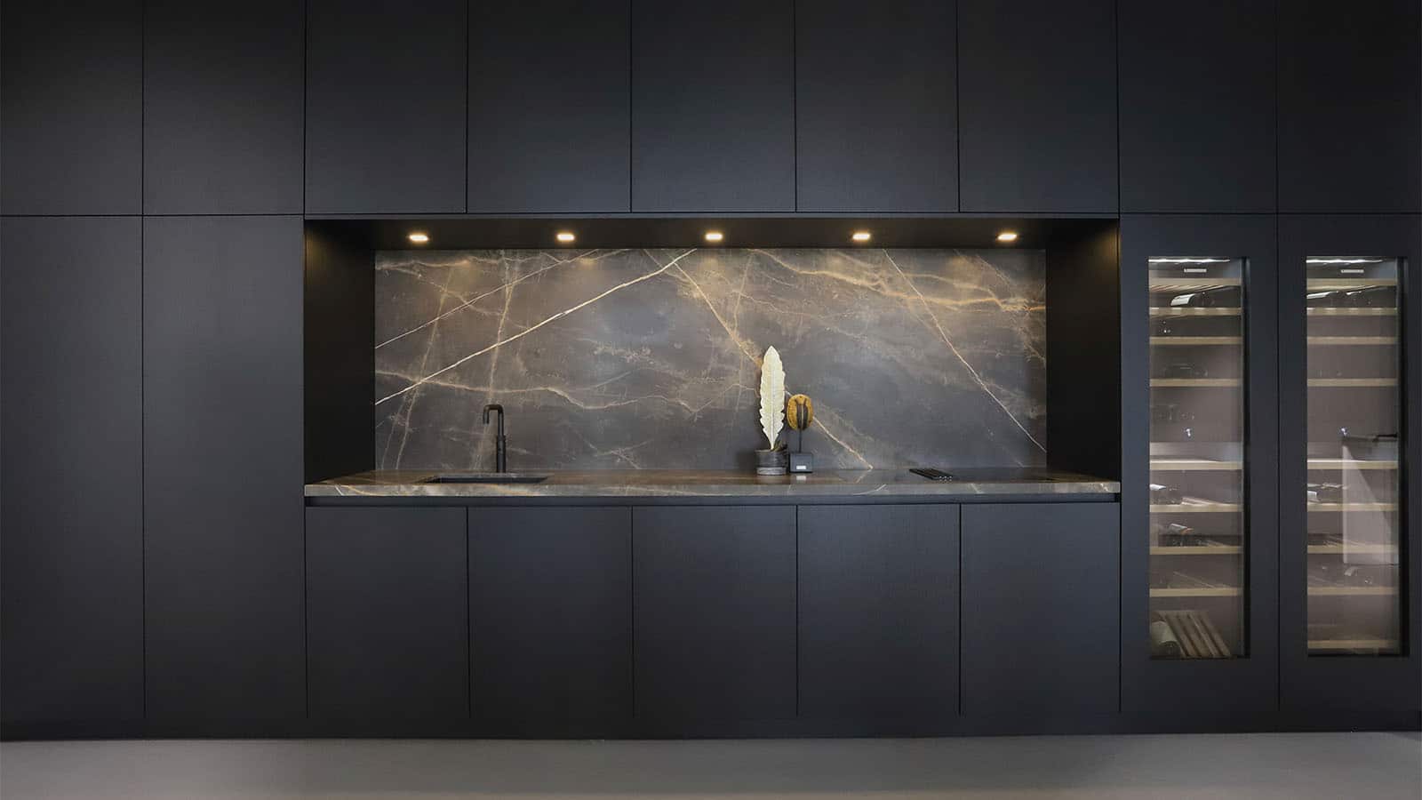 Minimalistische keuken met donkere kastenwand, een luxe marmeren achterwand en geïntegreerde verlichting