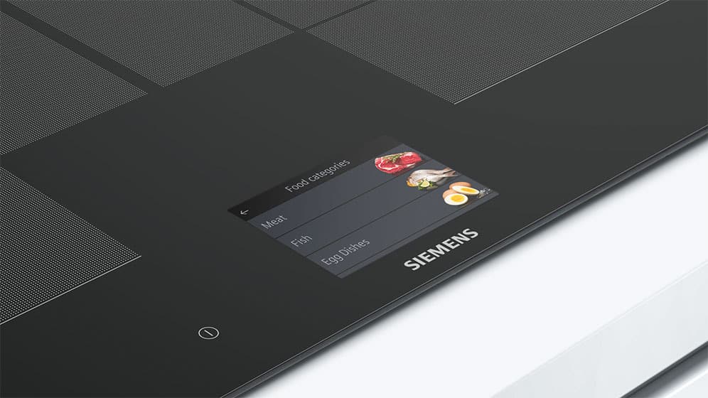 Een slimme inductie kookplaat van Siemens met een touchscreen waarop voedselcategorieën zoals vlees, vis en eiergerechten kunnen worden geselecteerd, waardoor de kookinstellingen automatisch worden aangepast.