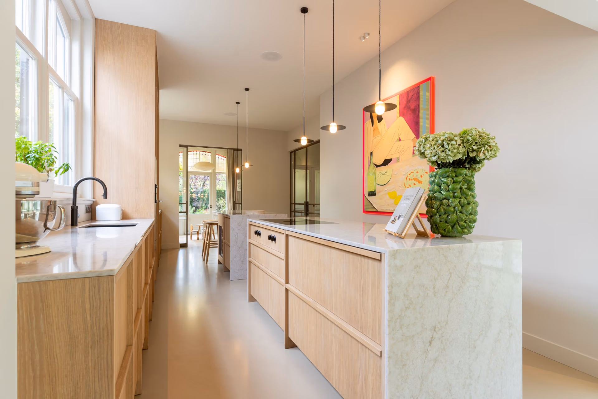 een lichte eikenhouten japandi keuken, met hangende lampen, quooker, en diverse accessoires