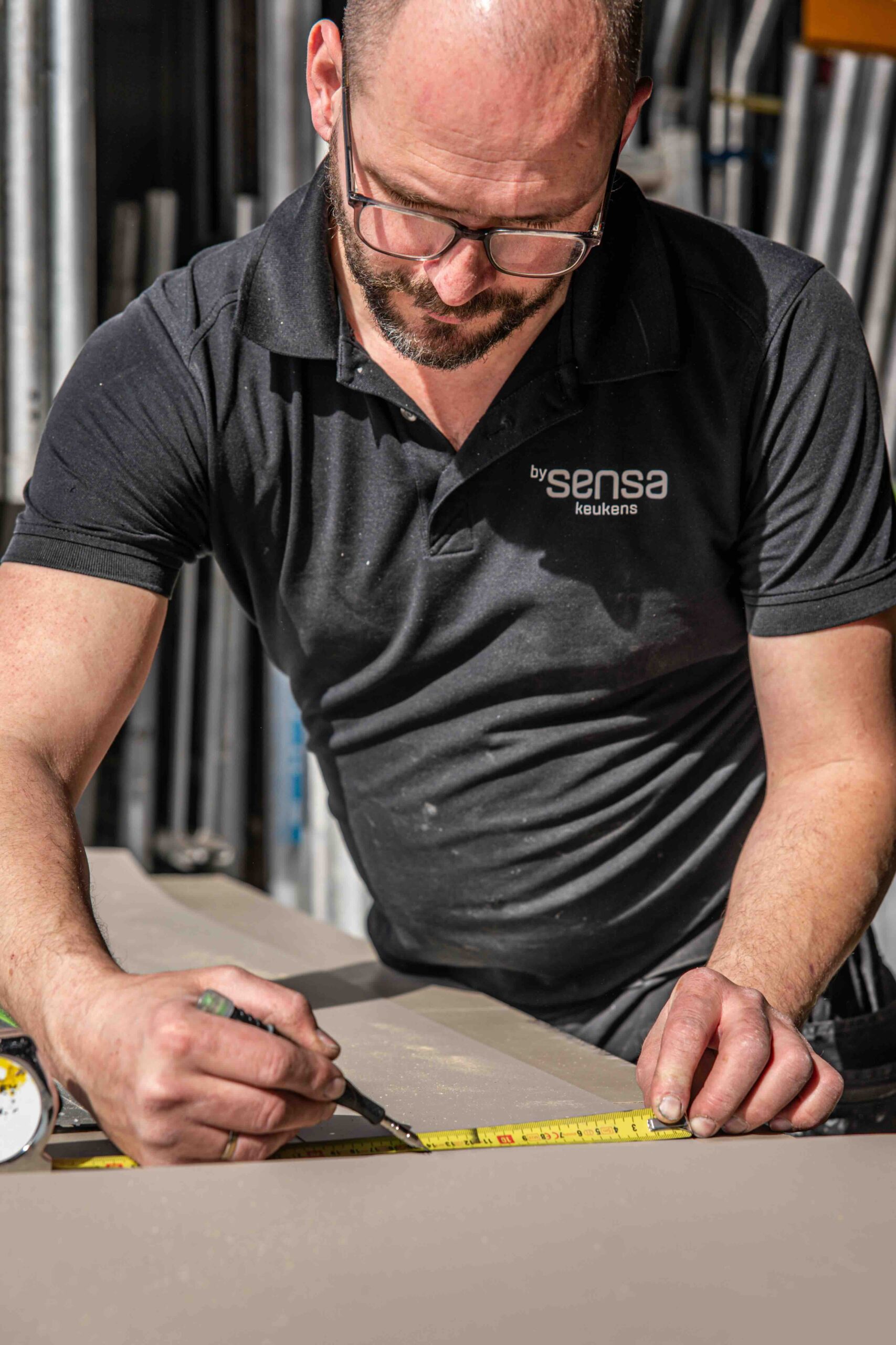 Man met potlood in de hand en meetlint om maat op te nemen voor het maken van een maatwerkkeuken