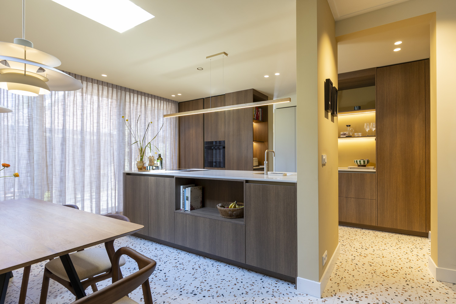 Luxe Japandi keuken in Zeist door BY SENSA, met een licht eiken kookeiland, composiet werkblad en een terrazzo vloer.