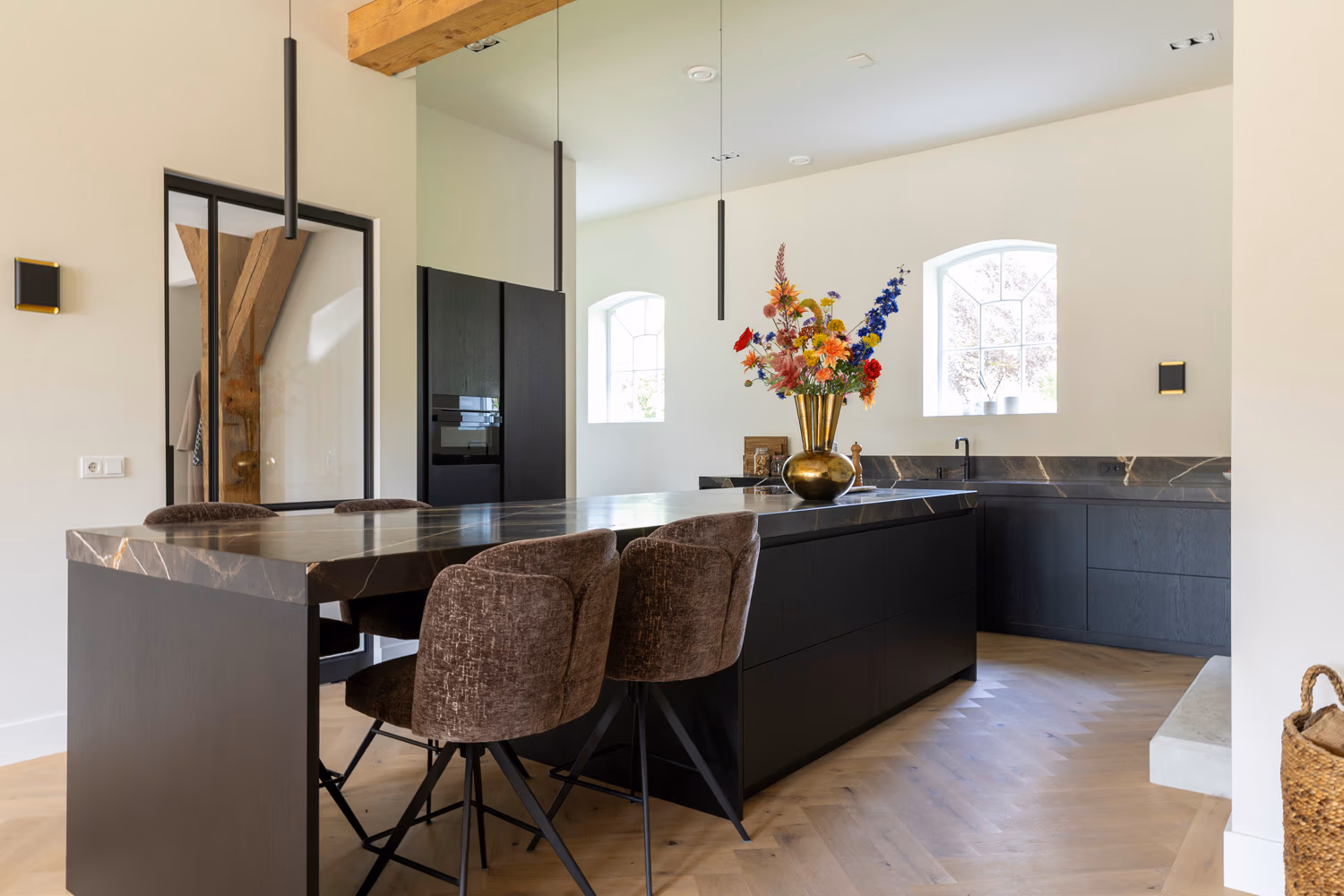 Design kookeiland van zwart eiken met een doorlopend marmeren blad en luxe barkrukken.